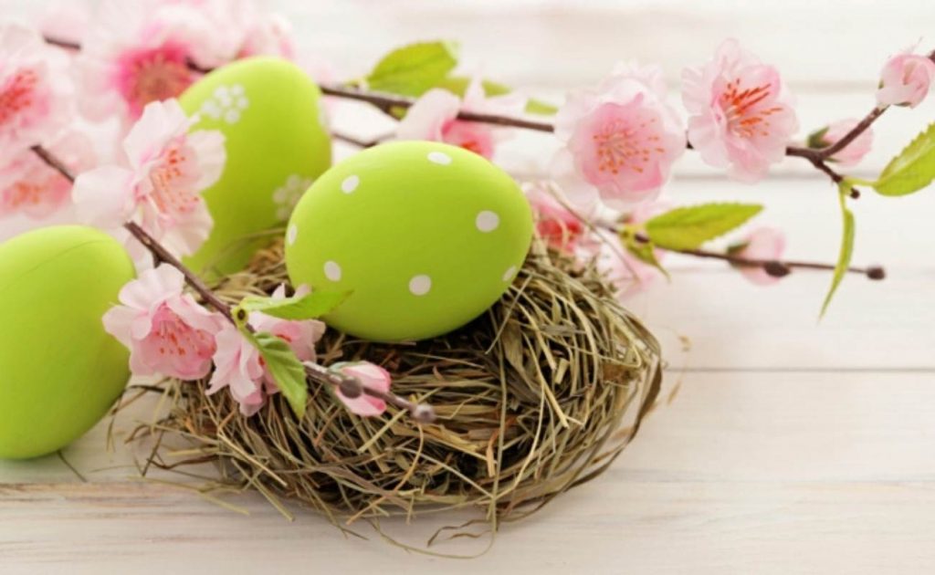 Place card o centro de mesa en forma de nido con paja, flores, ramas y huevos de colores.