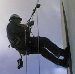 Trabajador colgando con cuerdas y cuerdas en el exterior del edificio